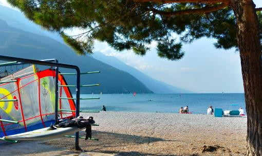Peaceful beach, colorful sails, serene mountains, and sea breeze.